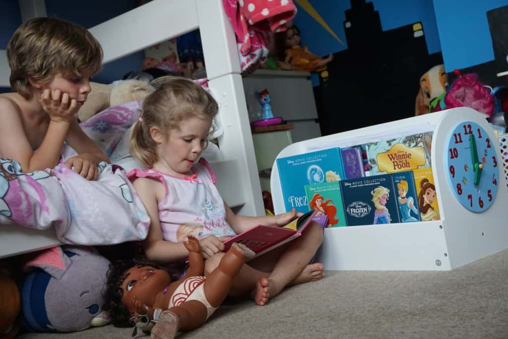 Bambini e lettura: due bimbi leggono un libro accanto alla loro libreria Tidy Books.
